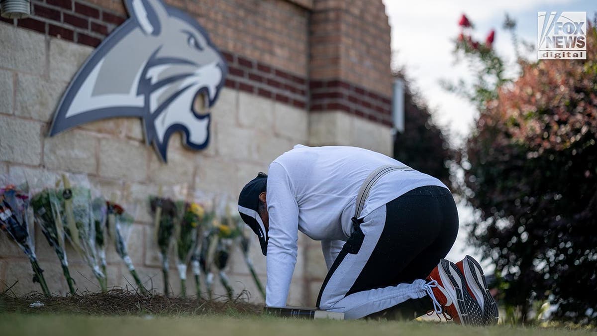 A woman kneels by a memorial to the slain in the Apalachee school shooting in Gerorgia