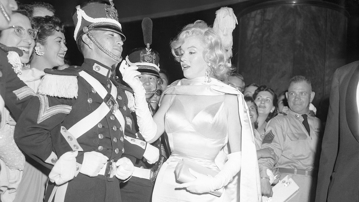 Marilyn Monroe meeting an English guard in a glamorous gown.