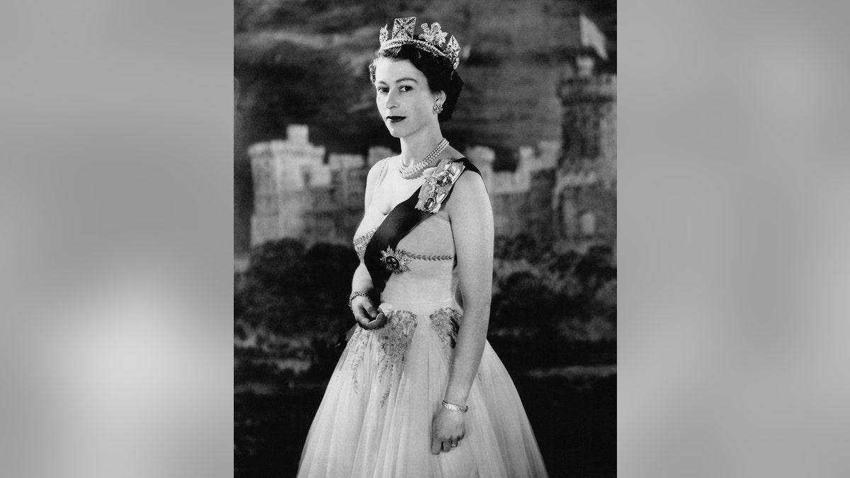 Queen Elizabeth wearing a royal sash and gown in a regal pose.