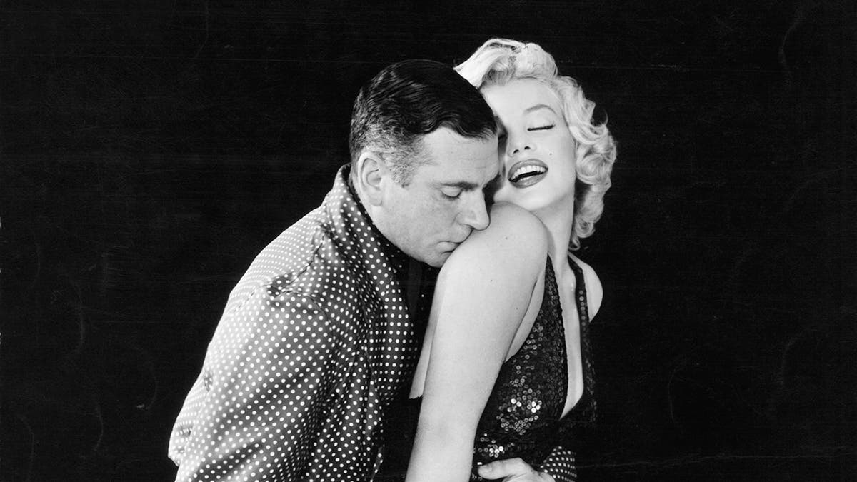 Marilyn Monroe being kissed on the shoulder by Laurence Olivier.