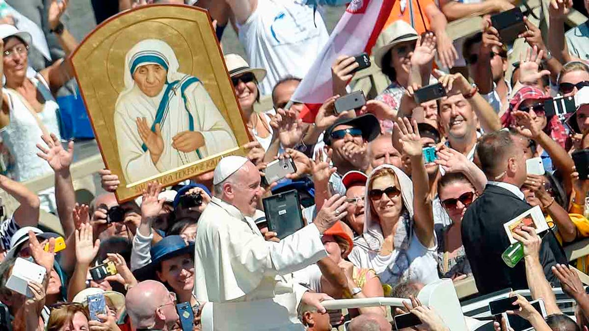 Pope Francis and a crowd holding a picture of Mother Teresa