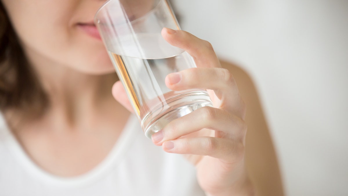 Happy beautiful young woman drinking water